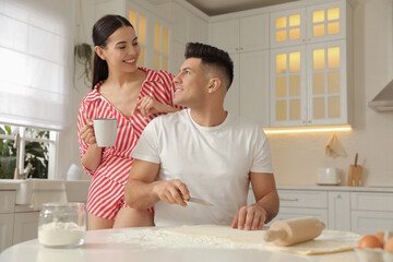 Canvas Print - Happy couple wearing pyjamas and cooking together in kitchen