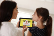 Mother using parental control app on tablet to ensure her child's safety at home