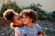 © Erin Brant/Stocksy - Young girl kissing sister on lap