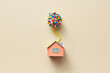 © Yaroslav Danylchenko/Stocksy - Beige papercraft house model with balloons