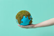© Yaroslav Danylchenko/Stocksy - Woman holding earth globe with green moss on hand