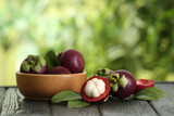 Delicious ripe mangosteen fruits on wooden table outdoors, space for text