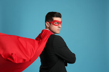 Wall Mural - Man wearing superhero cape and mask on light blue background