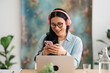 © Studio Marmellata/Stocksy - Cheerful woman using smartphone and recording podcast in studio