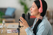 © Studio Marmellata/Stocksy - Asian woman in headphones speaking in mic in studio