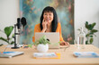 © Studio Marmellata/Stocksy - Positive Asian woman looking at camera and recording podcast