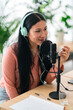 © Studio Marmellata/Stocksy - Glad woman recording podcast in headphones in studio