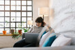 © Mihajlo Ckovric/Stocksy - Young businesswoman sitting at the couch in the office using her laptop