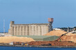 © Rowena Naylor/Stocksy - Wheat silos and logging storage at port ready for export