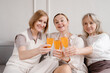 © Alina Hvostikova/Stocksy - Company of smiling women clinking glasses during celebration at home