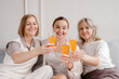 © Alina Hvostikova/Stocksy - Company of smiling women clinking glasses during celebration at home