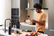 © Ivan Gener/Stocksy - Man checking his phone and making dinner