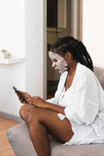 Woman In Sheet Mask Using Smartphone At Home