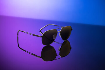 Sticker - Black sunglasses on blue reflective surface, closeup. Product photography and fashion concept