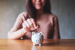 © Farknot Architect - Closeup image of a woman putting coins into piggy bank for saving money concept
