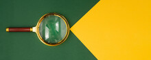 Magnifying Lens Over Green Background With Yellow Paper Beam With Copyspace For Text. Banner With Golden Loupe.