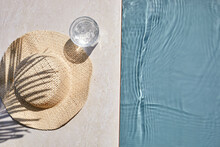 Summer Vacation. Hat On The Travertine Stone By The Beautiful Swimming Pool. Blue Sea Surface With Waves, Texture Water.