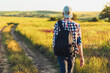 © Shopping King Louie - Active tourist, a man with a briefcase in nature, a hipster in a cap is walking along a path on a green hill, healthy lifestyle