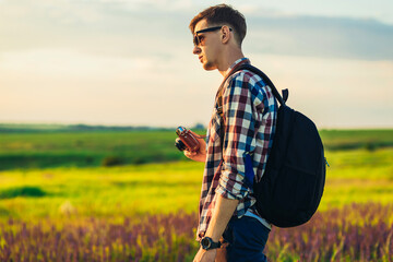 Wall Mural - Young male tourist, in sunglasses, with a camera, in nature, spending time in a hike, on the field