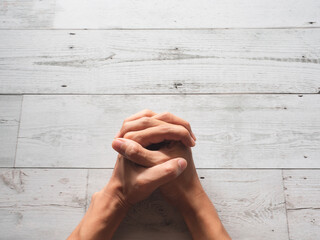 Wall Mural - Closeup praying hands fist and sunlight nature shadow on wood table top view