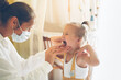 © natalialeb - funny little girl Toddler shows her throat to nurse in mask and white coat, calling doctor at home, patronage. Examination of pediatrician in a real interior,concept of medicine and disease prevention