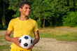 © Serhii - Happy African-American man holding soccer ball while standing outdoors in park