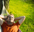 portrait of attractive nerd   man with glasses in the park with green lawn have a nice sunset in  the hammock  . Happy procrastination
