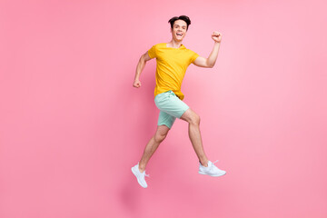 Poster - Full size profile side photo of young guy happy positive smile jump up go walk run isolated over pink color background