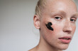 © Anna Tabakova/Stocksy - Young model with black scrub on face