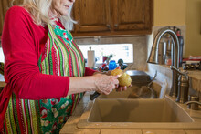 Older Lady Peeling Potatoes In A Home Kitchen At Christmas