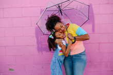 Mother And Daughter Hugging Under Umbrella