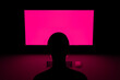 © Marcos Osorio/Stocksy - Gamer in front of computer with fuchsia screen