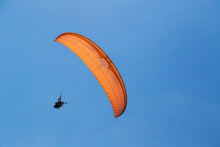 Tandem Orange Paragliding Against A Blue Sky, Sunny Day