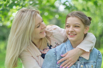 Wall Mural - happy mother with her daughter hugging a teenager in the summer. Caring happy mother enjoy day with teenage girl child, laugh have fun. Mother giving her daughter advice.