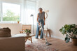 © BONNINSTUDIO/Stocksy - Mature housewife cleaning floor in living room