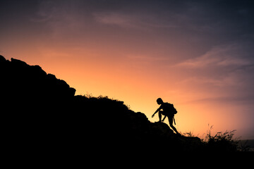 Hiker silhouette starting his climb up the mountain. Outdoor adventure, motivation and active sport concept. 