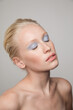 © Anna Tabakova/Stocksy - Young freckled model with blue eyeshadows