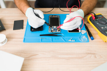 Wall Mural - Top view of a technician checking the connections on a smartphone