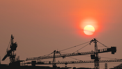 silhouette of construction site with tower crane during sunset