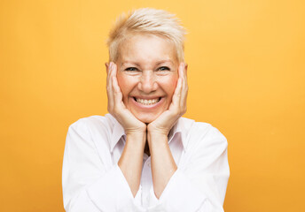 Portrait of senior woman with cute smile over yellow background