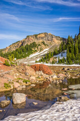 Wall Mural - rocky volcanic mountain landscape with colored rocks, melting snow, and a blue sky.