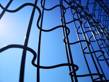 Low Angle View Of Metal Fence Against Blue Sky
