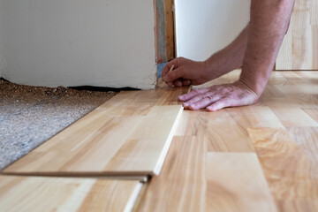 Caucasian man installing wood parquet board during flooring work