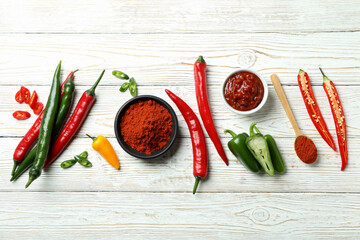 Poster - Hot peppers, sauce and powder on white wooden background