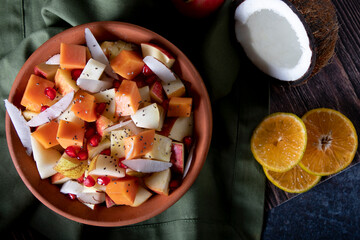 Canvas Print - Organic vegan Fruit salad of papaya apple kiwi banana pomegranate raisins for healthy lifestyle dressed up in a bowl on chopping board