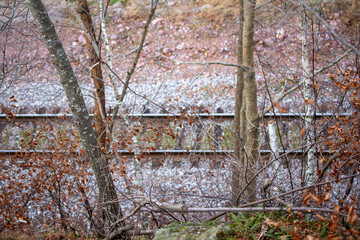 Wall Mural - abstract high angle view of a winter snow dusted railroad track at the bottom of a rustic ravine wit