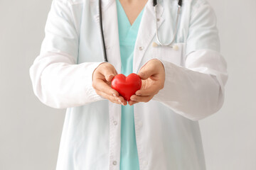 Wall Mural - Female cardiologist with red heart on grey background