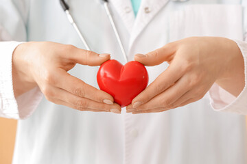 Wall Mural - Female cardiologist with red heart, closeup