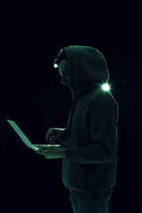 Silhouette of hacker with laptop on dark background