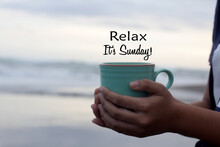 Relax. It's Sunday. Hello Sunday Weekend Concept With A Person Holding A Cup Of Coffee In Hand On Beach Background. Happy Sunday. Self Love Care And Happiness Concept.